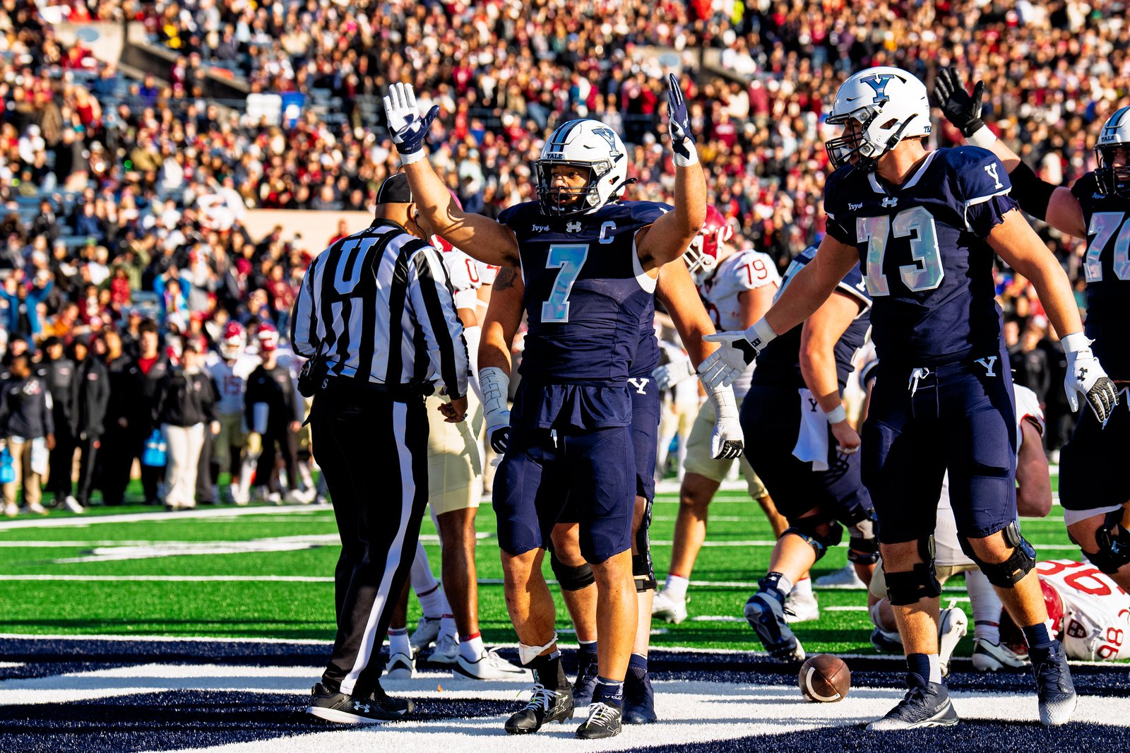 Yale team captain number 7 raises his arms in celebration against Harvard
